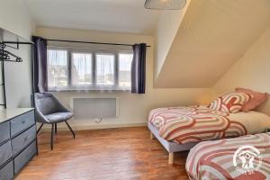 a bedroom with two beds and a chair and a window at Le palmier in Penvénan
