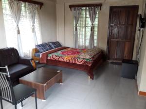 a bedroom with a bed and a chair and a table at Streamside Guest House in Mawlynnong
