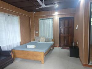 a bedroom with a bed and a chair and a window at Streamside Guest House in Mawlynnong