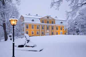 a large yellow building with a street light in the snow at Mustion Linna / Svartå Manor in Svartå