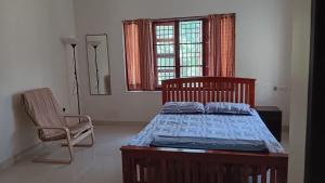 a bedroom with a bed and a chair and a window at Pratheeksha Homestay in Kannur