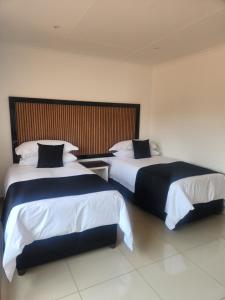 a hotel room with two beds and a headboard at The Pebbles-UA in Mahikeng