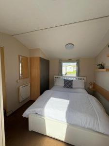 a bedroom with a large white bed with a window at Static home sleeps 6 in Dawlish Warren