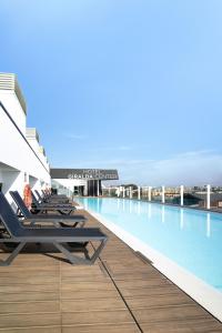 a row of chaise lounge chairs on a swimming pool at Hotel Giralda Center in Seville