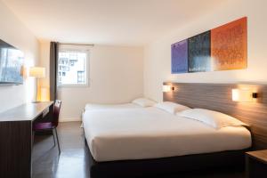 a hotel room with two beds and a desk at The Originals Residence Appart Hôtel Hévéa Valence in Valence +42 photos