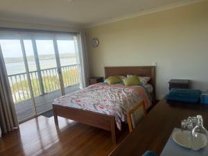 a bedroom with a bed and a table and a balcony at Pillais B and B in Albany