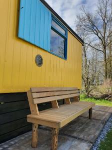 a wooden bench sitting outside of a yellow house at De Maanloper in Bant +6 photos