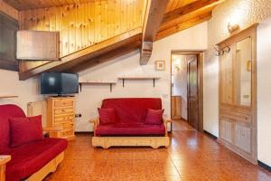 a living room with a red couch and a tv at Rifugio del Sole Apartment in Monclassico