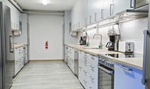 a large kitchen with white cabinets and appliances at Forenom Hostel Gothenburg Säve in Gothenburg