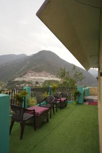 a group of chairs and tables on a balcony with a mountain at Sangam View Homestay Devprayag in Devaprayāg
