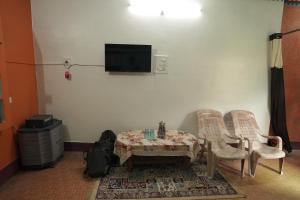 a room with a table and two chairs and a tv at Sangam View Homestay Devprayag in Devaprayāg