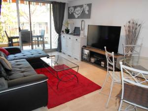 sala de estar con sofá, mesa y TV en Appartement Marco Polo en Mandelieu-la-Napoule
