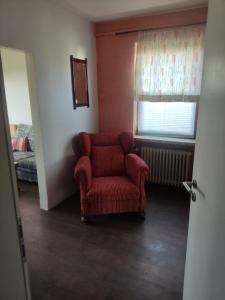 a living room with a red chair and a window at Unterkunft Mau in Rotenburg an der Wümme