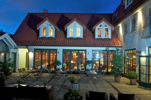 ein großes Haus mit einem Innenhof mit Tischen und Stühlen in der Unterkunft Romantik Hotel Kaufmannshof in Bergen auf Rügen