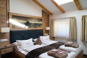 ein Schlafzimmer mit zwei Betten und einem Gemälde an der Wand in der Unterkunft Panorama Resort Taljörgele in Ridnaun + 37 Fotos
