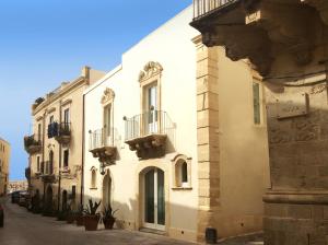 ein weißes Gebäude mit Balkon auf einer Straße in der Unterkunft Re Federico Boutique Hotel in Syrakus