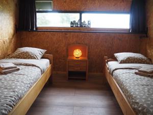 two beds in a room with a lamp on a night stand at Molesicht en Lânsicht in Workum