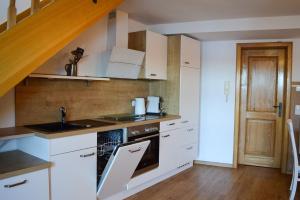 a kitchen with white cabinets and a sink and a stove at Ferienwohnung Seeufer in Bad Bayersoien