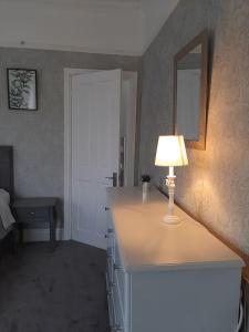 a room with a table with a lamp and a mirror at Stonehouse Apartment in Mexborough