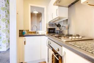 a kitchen with white cabinets and a stove top oven at Stonehouse Apartment in Mexborough