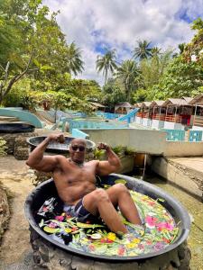 a man sitting in a pool on a surfboard at Tuburan Resort in Panong