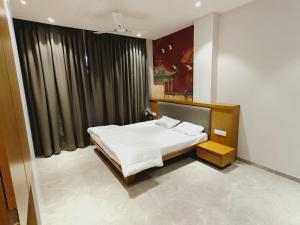 a bedroom with a white bed and black curtains at LL Palace in Hinganghāt
