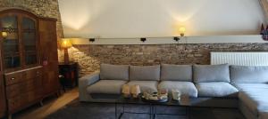 a living room with a couch and a stone wall at L'Eaubergerine in Herbeumont