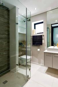 La salle de bains est pourvue d'une douche, de toilettes et d'un lavabo. dans l'établissement Seacrest Luxury Beachfront Apartment - Blouberg Beach, à Bloubergstrand
