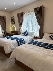 a bedroom with two beds and a window at Long Bình Hotel in Dong Hoi