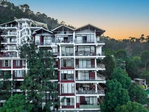 a tall building with trees in front of it at Nirvana By Nest Kasauli 2 BHK Luxury Apartment Rooftop Cafe Free Parking in Kasauli