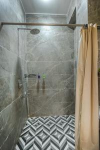 a bathroom with a shower with a black and white tile floor at Nirvana By Nest Kasauli 2 BHK Luxury Apartment Rooftop Cafe Free Parking in Kasauli +34 photos
