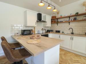 a kitchen with white cabinets and a wooden counter top at Trillo Lodge in Colwyn Bay