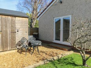 a patio with two chairs and a table in front of a house at Trillo Lodge in Colwyn Bay