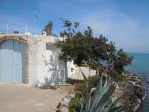 a building on the side of the ocean with a tree at Stalida Holiday Home in Stalida