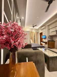 a vase with pink flowers on a table in a living room at Luxe Haven Stays - Luxury Studio , Premium Stay in Noida