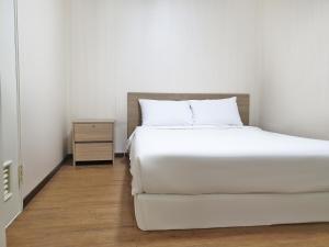 a bedroom with a white bed and a night stand at Jiri Mountain Ilsung Condo in Namwon +3 photos