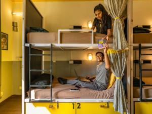 a man and a woman standing on top of bunk beds at The Hosteller Delhi in New Delhi