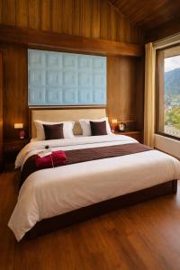 a large bed in a room with a large window at Aura Montane luxury cottages in Manāli