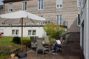 a woman sitting at a table under an umbrella at Haus am Mühlberg in Modautal