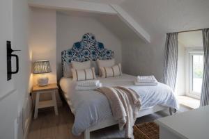 a white bedroom with a large bed with a blue headboard at Rose Cottage in Wadebridge