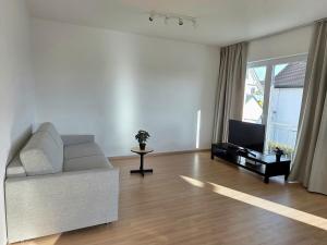 a living room with a white couch and a television at Apartment Ilmtalblick in Pfaffenhofen an der Ilm