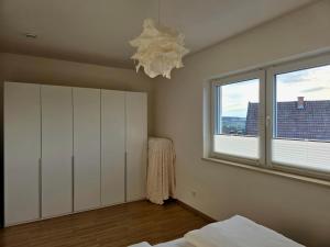 a bedroom with a bed and a window and a chandelier at Apartment Ilmtalblick in Pfaffenhofen an der Ilm
