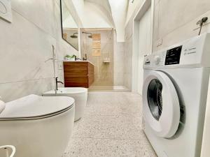a white bathroom with a toilet and a washing machine at Casina Mameli in Nardò