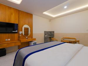 a bedroom with a white bed and a tv at Wana Kubu Homestay in Kuta
