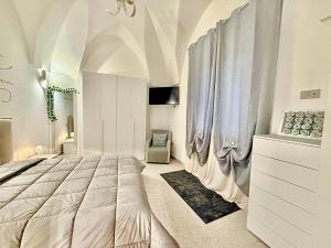 a bedroom with a large white bed and curtains at Casina Mameli in Nardò +4 photos