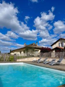 a swimming pool with lounge chairs and a house at Les Marchettes in Saint-Nexans