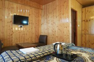 a bedroom with a bed and a desk and a tv at The Himalayan Drift Cottages in Vashisht