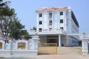 a white building with a fence in front of it at VGN Convention Centre in Vāniyambādi +18 photos