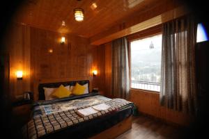 a bedroom with a bed and a window with a view at The Himalayan Drift Cottages in Vashisht