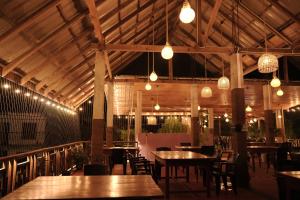 a restaurant with wooden tables and chairs and lights at SNP Star Guest House in Trincomalee